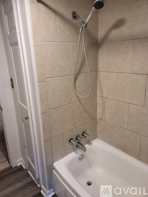 A white bathtub with a shower head and hand held shower.