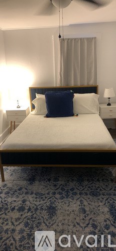 A bedroom with a bed, two lamps, and a ceiling fan.