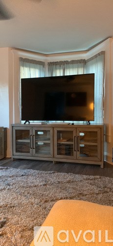 A flat screen TV is mounted on a wall above a wooden cabinet.