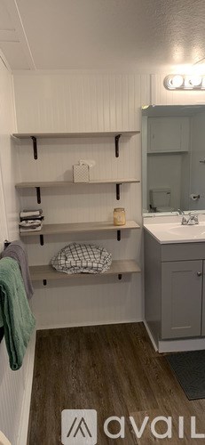 A bathroom with a towel hanging on the wall and a mirror above the sink.