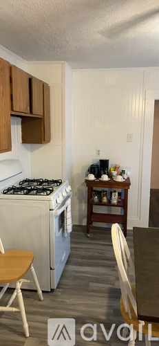 A kitchen with a white stove top oven and wooden cabinets.