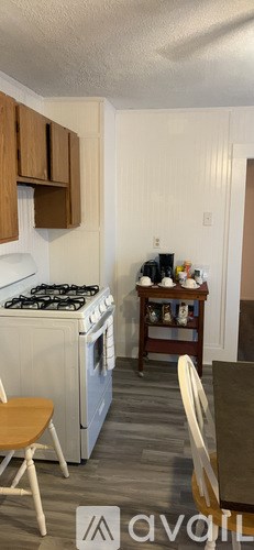 A kitchen with a white stove top oven and wooden cabinets.