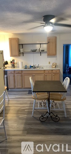 A kitchen with a table and chairs in the foreground and a refrigerator in the background.