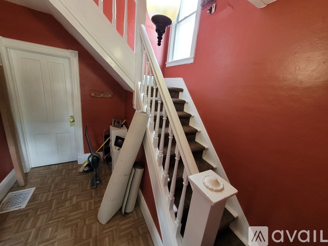 A staircase with a red wall and a white door.