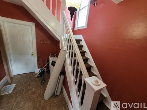A staircase with a red wall and a white door.