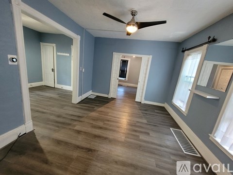 A room with a ceiling fan and wooden flooring.