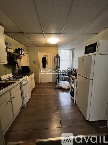 A kitchen with white appliances and wooden floors.