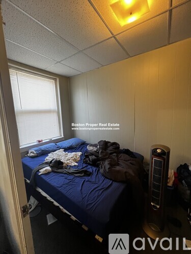 A bedroom with a bed, window, and a fan.