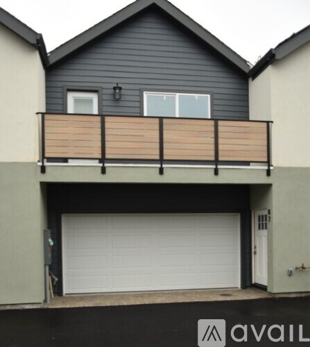 A black house with a white garage door and a balcony.