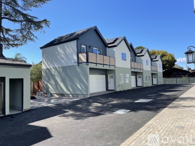 A row of modern houses with garages are lined up on a street.