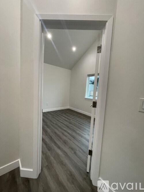 A hallway with a wooden floor and white walls.