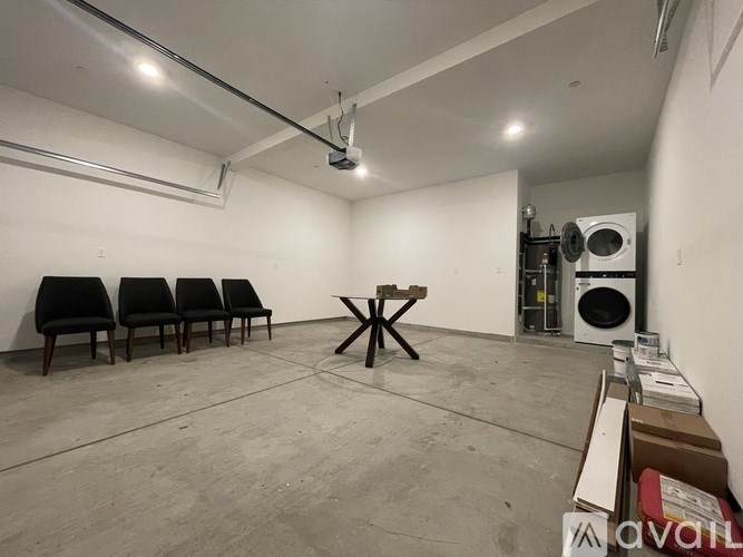 A room with a white wall, a black chair, a wooden table, and a white ceiling.