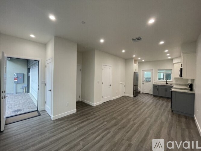 A spacious room with wooden flooring and white walls.
