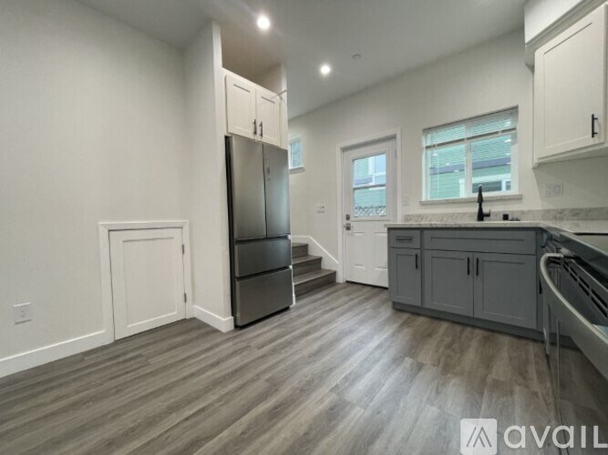 A kitchen with a refrigerator, cabinets, and a staircase.