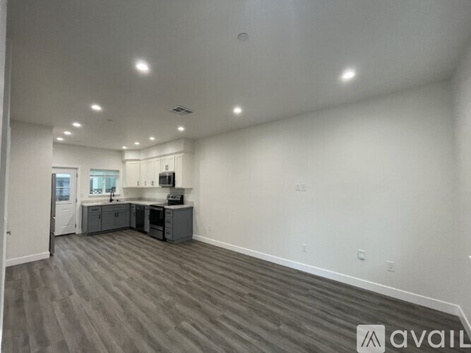 A spacious room with a kitchen area and grey flooring.