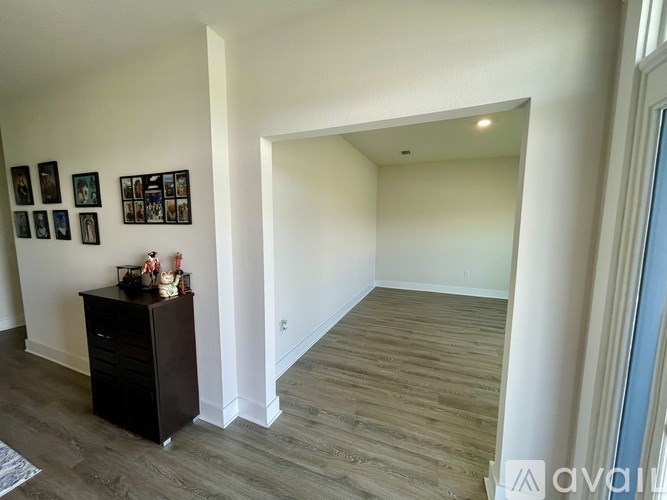 A room with a wooden floor and a cabinet with some items on top of it.