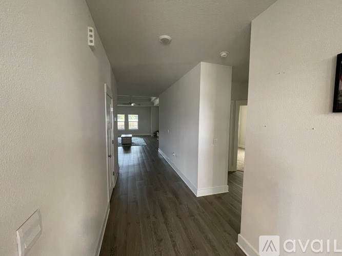 A long hallway with wood floors and white walls.