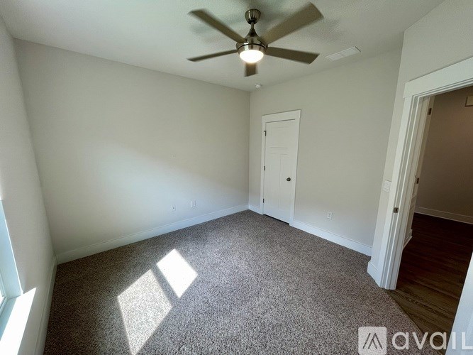 A room with a ceiling fan and carpeted floor.