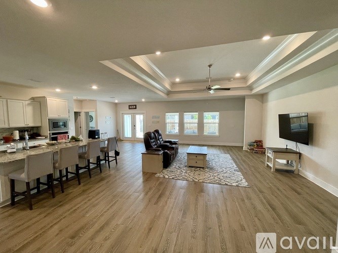 A spacious living room with a kitchen area in the background.