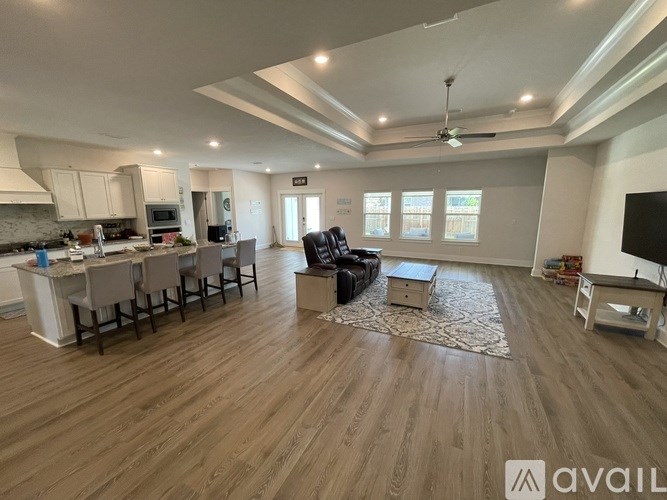 A spacious living room with a kitchen area in the background.
