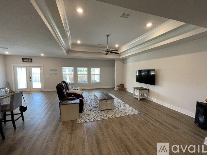 A spacious living room with a television, a couch, and a rug.