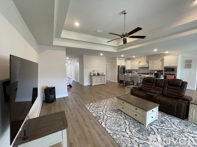 A living room with a brown couch and a ceiling fan.