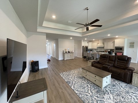 A living room with a brown couch and a ceiling fan.