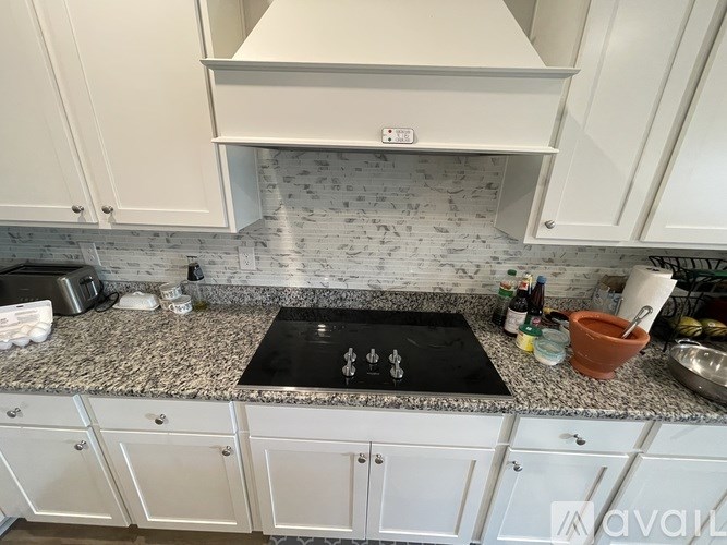 A kitchen with a black stove top and white cabinets.
