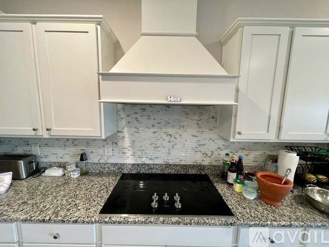 A kitchen with a granite countertop and a stove top with a dollar sign on it.