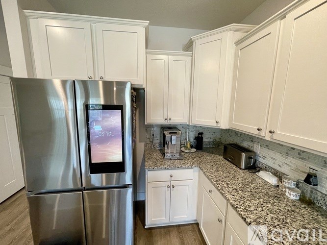 A kitchen with a stainless steel refrigerator and white cabinets.