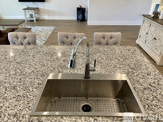 A modern kitchen with a granite countertop and a stainless steel sink.