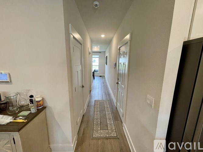 A long hallway with a rug on the floor and a cabinet on the left side.