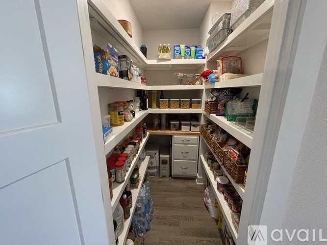 A pantry with white shelves and various food items.