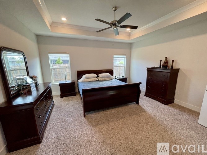 A bedroom with a bed, dresser, and a ceiling fan.