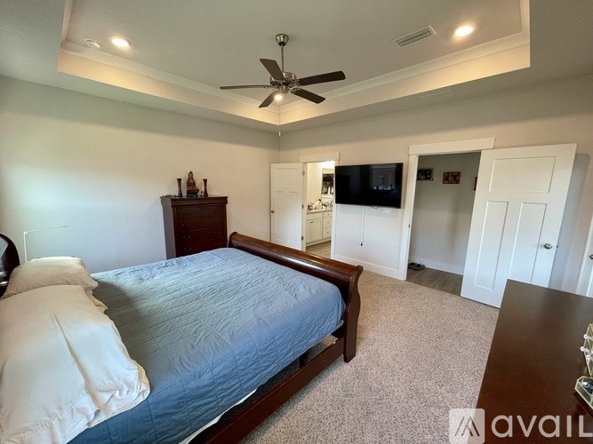 A bedroom with a bed, dresser, and ceiling fan.