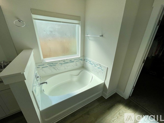 A white bathroom with a tub and a window.
