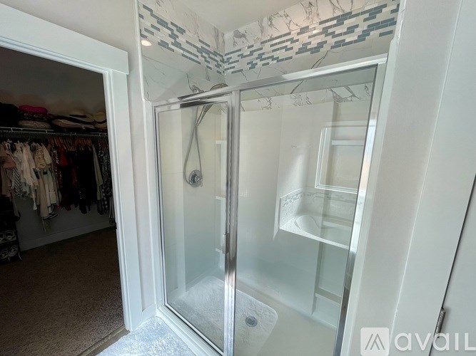 A bathroom with a walk-in shower and a glass door.