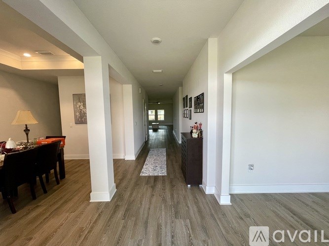 A long hallway with a table and chairs on the left and a framed picture on the wall.