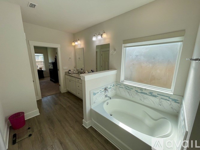 A white bathroom with a tub and a window.