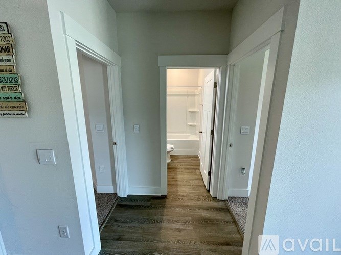 A hallway with white walls and wooden flooring.