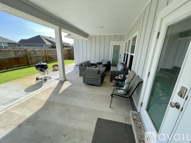 A sunny day at a covered outdoor patio with a couch, chairs, and a baby stroller.