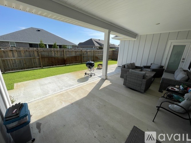 A patio with a couch, chair, and table with a view of a backyard.