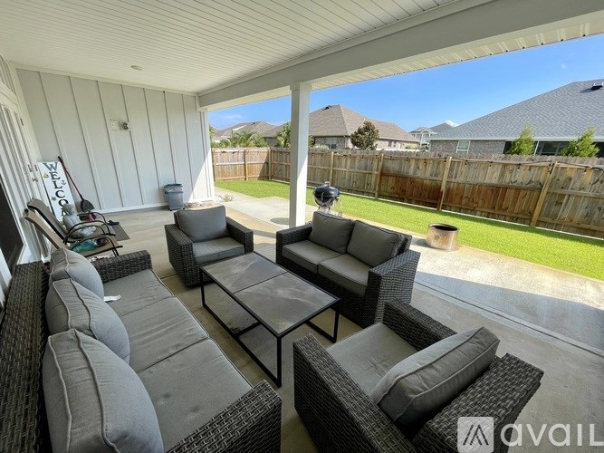 A patio with a grey sofa and a glass table.