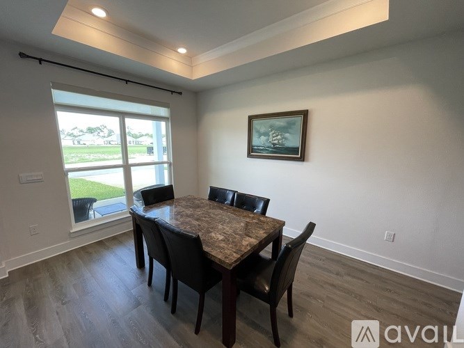 A dining room with a table and chairs and a painting on the wall.