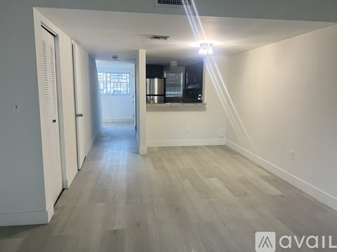 A long hallway with a door on the left and a window on the right.