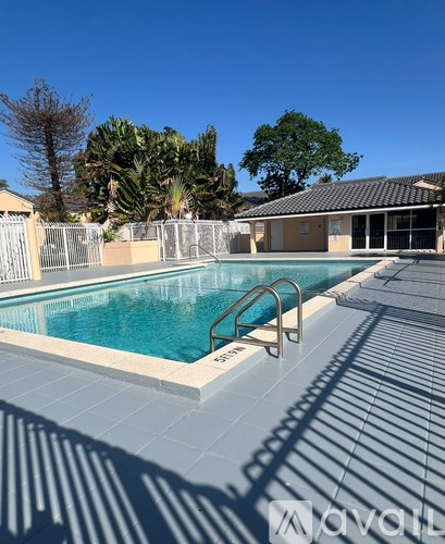 A pool surrounded by a white fence and trees.