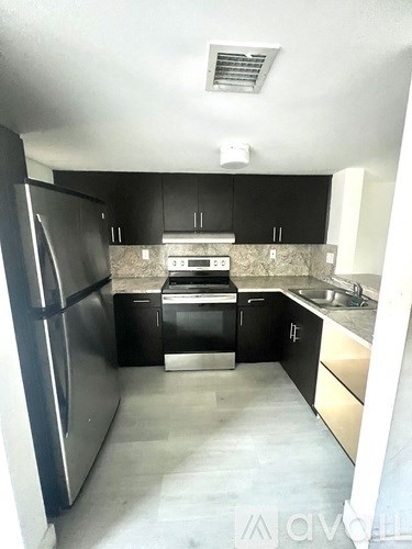 A kitchen with black cabinets and stainless steel appliances.