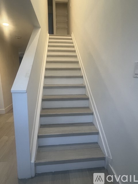 A staircase with a white railing and grey steps.