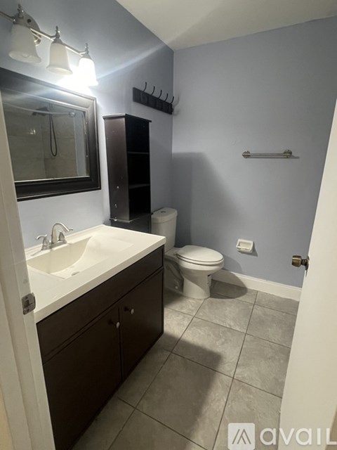 A bathroom with a toilet, sink, and mirror.