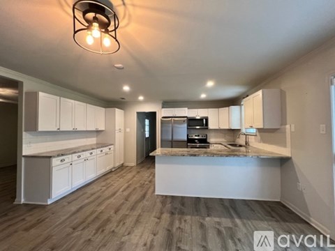 A modern kitchen with white cabinets and a wooden floor.